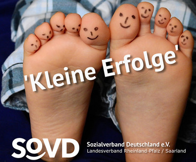 Die Sohlen von zwei Kinderfüßen. Die Zehen sind mit Gesichtern bemalt. Titel: Kleine Erfolge 