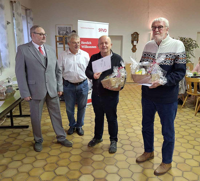 Gruppenbild mit vier Männern. Zwei halten eine Urkunde und einen Präsentkorb in den Händen. 