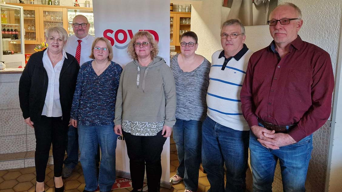 Sieben Personen vor einem SoVD-Aufsteller. 