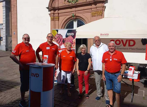 Menschen in roten SoVD-Shirts am Infostand. 