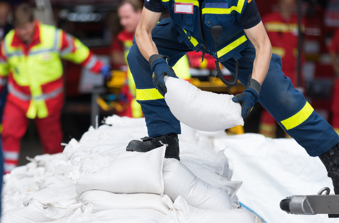 Ein Feuerwehrmann stapelt Sandsäcke