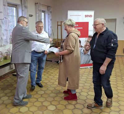 Mann und Frau erhalten Urkunde von einem Mann. 