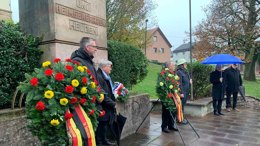 Ehrenmal und Menschen mit Kränzen