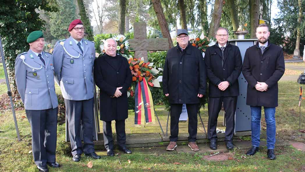 Gruppe von Soldaten und Zivilisten mit großem Kranz