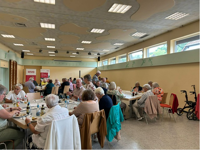 Saal mit vielen Menschen an Tischen